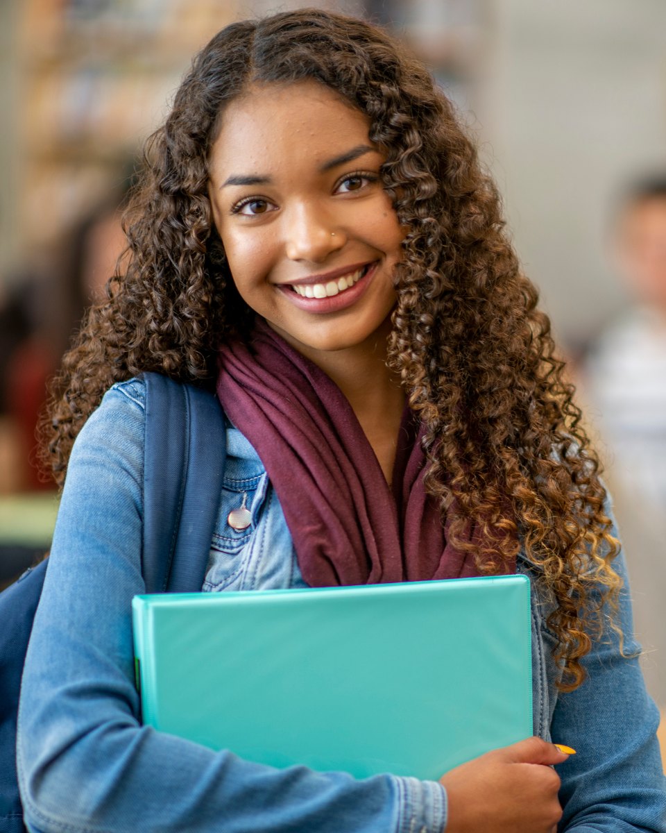 Smiling student holding a notebook: learn the skills, build your career