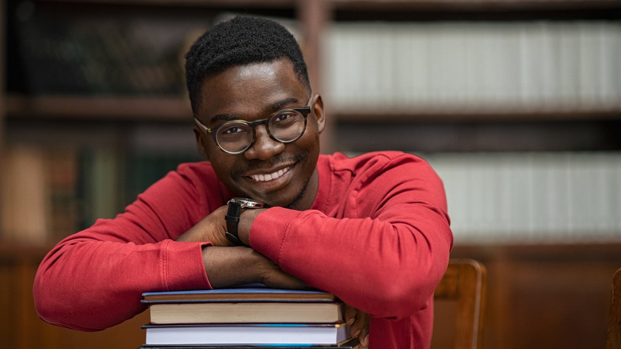 Smiling learner leaning on books: success through guidance