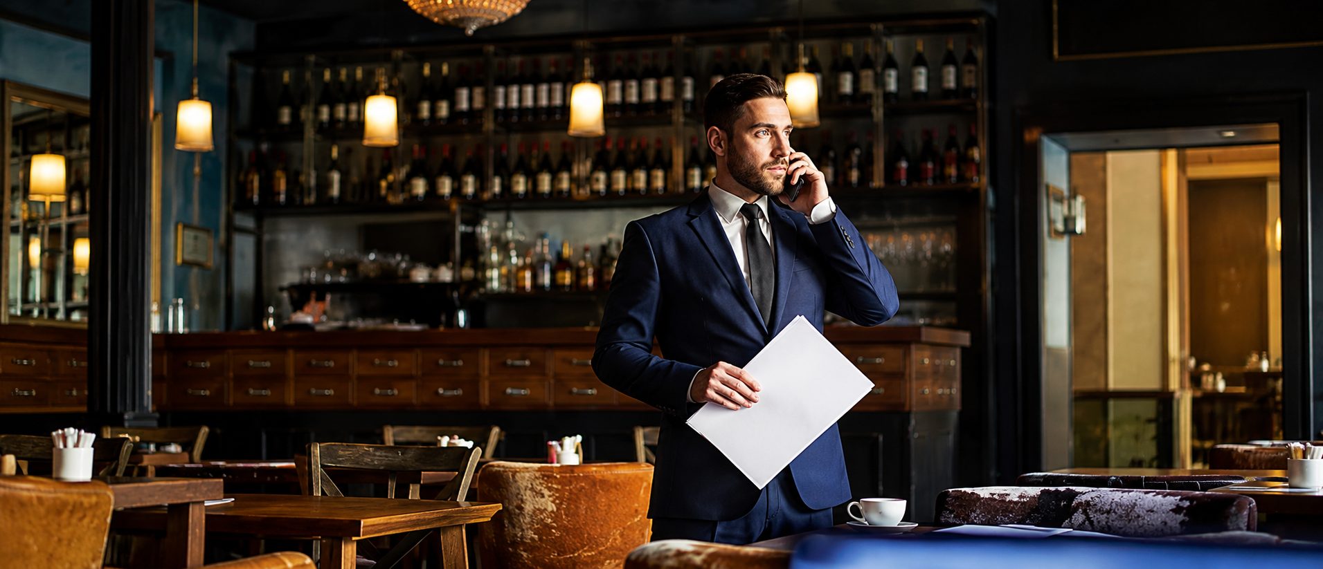Restaurateur au téléphone, un document à la main, dans sa salle