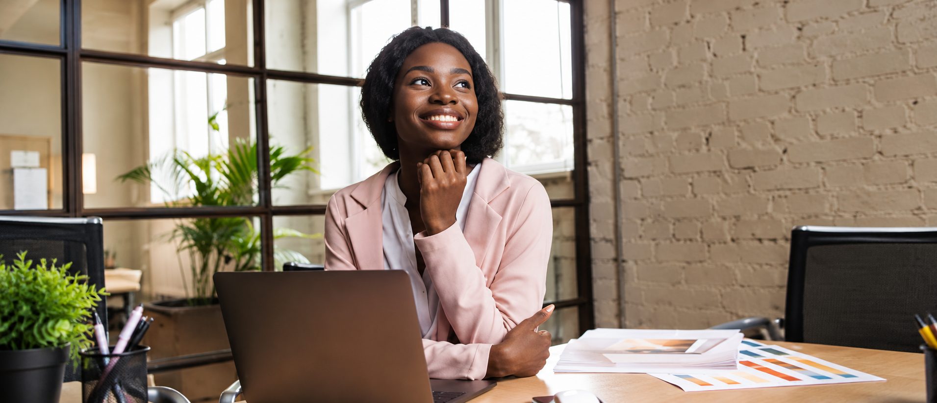 Entrepreneuse souriante devant son ordinateur portable, dans un bureau lumineux