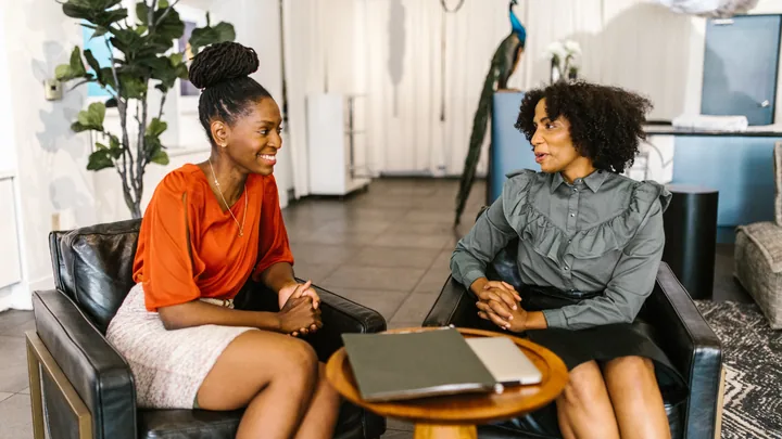 Deux femmes assises face à face dans des fauteuils, en pleine conversation